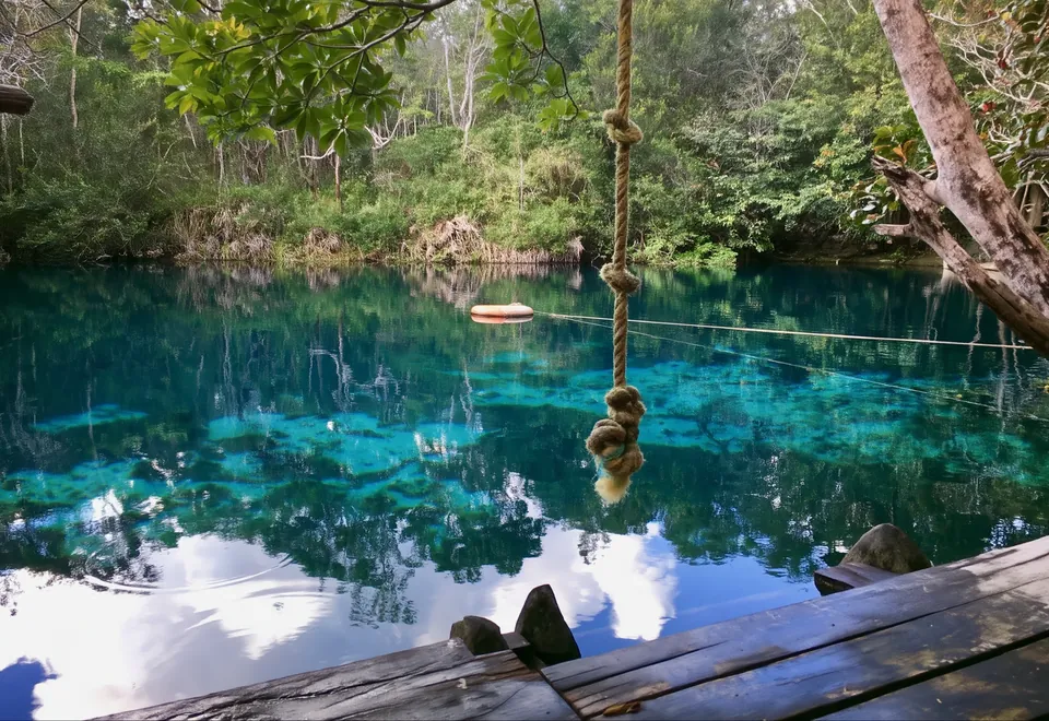 A rope hanging over the clear water of Cenote Car Wash, fringed by jungle, near Tulum